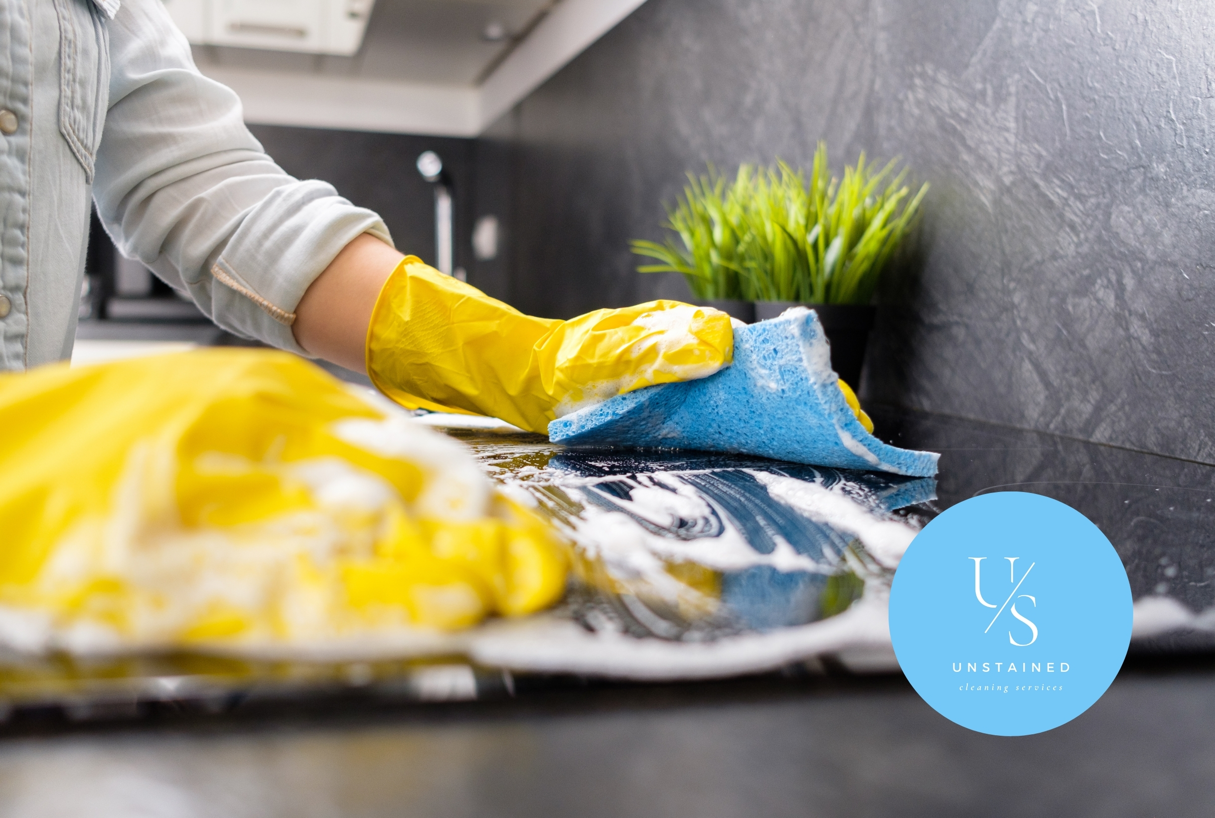 Gloved hand cleaning kitchen counter with sponge – Unstained Cleaning Services
